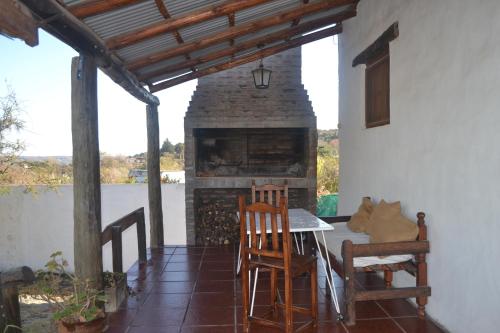 een patio met een open haard en een tafel en stoelen bij Cabañas Los Relinchos in Capilla del Monte