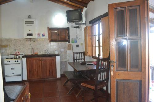 une cuisine avec une table et une cuisine avec une cuisinière dans l'établissement Cabañas Los Relinchos, à Capilla del Monte