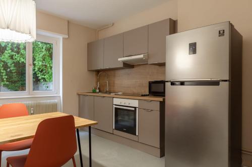 une cuisine avec un réfrigérateur en acier inoxydable et une table dans l'établissement Travel Homes - Le Freedom, chaleureux & spacieux, à Mulhouse