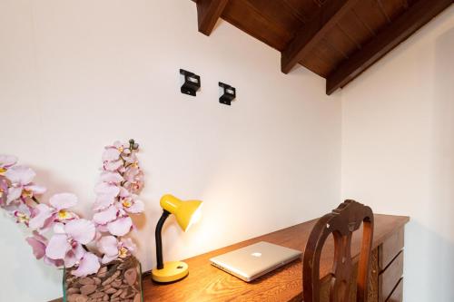 einen Schreibtisch mit einem Laptop und eine Vase mit Blumen in der Unterkunft 4 Suítes + Piscina e Área Gourmet | 3 Irmãos in Búzios