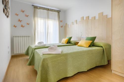 1 dormitorio con 2 camas con almohadas verdes y amarillas en OTAL URBAN de "Casa Otal", en Jaca