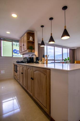 a kitchen with wooden cabinets and a counter top at Alcazar de Oviedo by EE Hoteles in Medellín