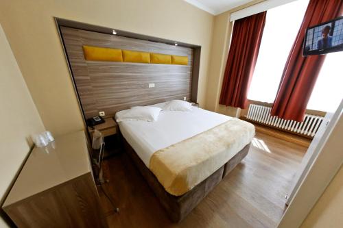 a bedroom with a large bed with a wooden headboard at Hotel de France in Brussels