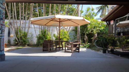 グアルジャにあるTombo Beach Hostel & Pousadaのパティオ(パラソルの下にテーブルと椅子付)