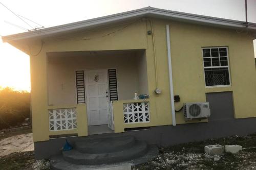 una pequeña casa amarilla con puerta y ventanas en Sasha’s Holiday Home Oistins Barbados en Christ Church