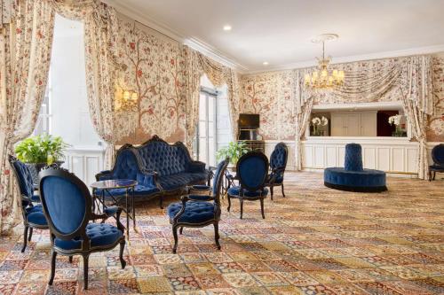 a living room with blue chairs and a chandelier at Grand Hotel de l'Opera - BW Premier Collection in Toulouse