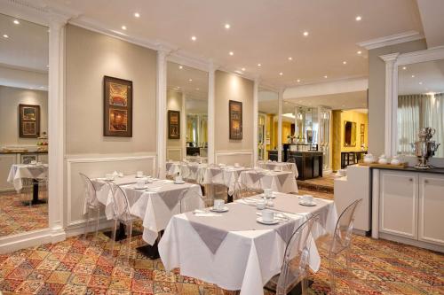 a dining room with white tables and chairs in it at Grand Hotel de l'Opera - BW Premier Collection in Toulouse