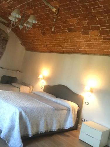 een slaapkamer met 2 bedden en een bakstenen muur bij La locanda del cuore in Carrù