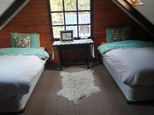 a attic room with two beds and a table at Refugio Las Raices in Malalcahuello