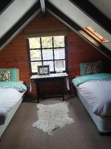 a attic room with two beds and a window at Refugio Las Raices in Malalcahuello