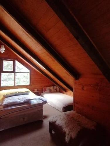 a attic room with two beds and a window at Refugio Las Raices in Malalcahuello