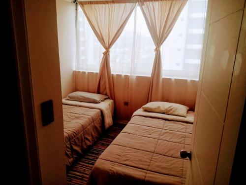 two beds in a room with a window at Viña del mar descanso y entretención in Viña del Mar