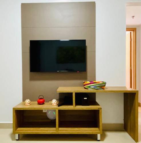 a living room with a tv and a wooden table at Flat 303 - Condomínio Park Veredas - Acesso ao Rio - Completo com ar no quarto e na sala in Rio Quente