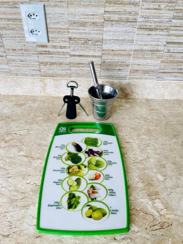 a green cutting board with vegetables on it at Flat 303 - Condomínio Park Veredas - Acesso ao Rio - Completo com ar no quarto e na sala in Rio Quente