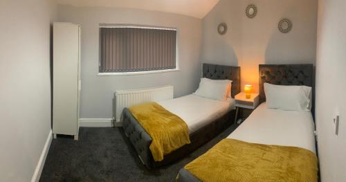2 camas en una habitación pequeña con ventana en Gateshead Serviced Apartment Ideal for Contractors and Vacationing, en Gateshead