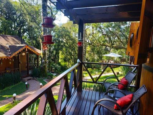 a porch with chairs and a bird feeder at Chalé Temático em Pipa de Vinho - Parada da Pipa Chalés in Canela