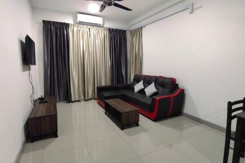 un soggiorno con divano nero e TV di Pangsapuri Ladang Tanjung a Kuala Terengganu