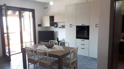 een keuken met een tafel met stoelen en een televisie bij Mare Dune Laghetto in Torre Dei Corsari