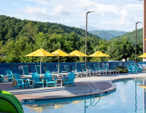a pool with blue chairs and tables and umbrellas at The Lodge at Camp Margaritaville in Pigeon Forge