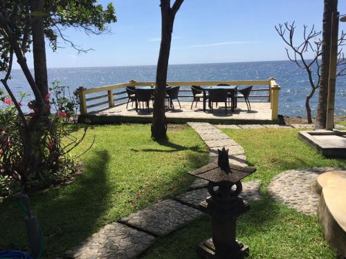 a garden with a table and chairs and the ocean at Bali Cottage Sambirenteng in Pabean Buleleng