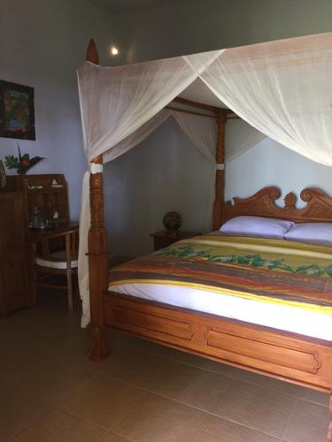 a bedroom with a wooden bed with a canopy at Bali Cottage Sambirenteng in Buleleng