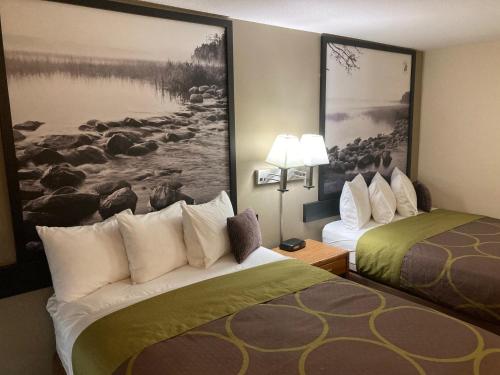 a hotel room with two beds and a painting on the wall at Super 8 by Wyndham Chisago City in Chisago City