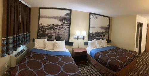 a hotel room with two beds and paintings on the wall at Super 8 by Wyndham Chisago City in Chisago City