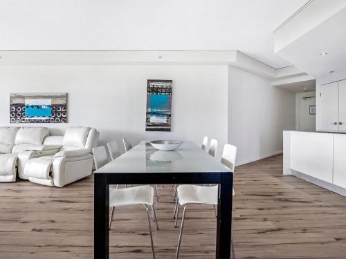 a dining room with a black table and white chairs at 3BR Apartment Hinterland Views - Sierra Grand CoastHM in Gold Coast