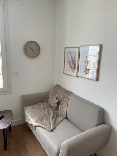 a couch in a living room with a clock on the wall at Le Poulorio 10 - T2 - Proche Gare By Locly in Lorient