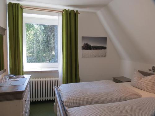 a bedroom with a bed and a window with green curtains at Ferienhotel Mühlleithen in Klingenthal