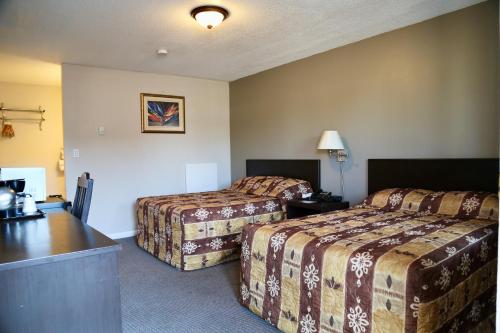 um quarto de hotel com duas camas e uma secretária em Blue Bell Inn em Fort Nelson