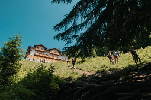 a group of people walking on a trail in front of a house at Cabana Fantanele in Ceahlău
