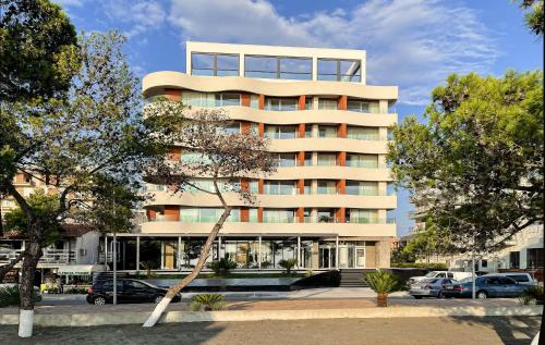 a tall building with cars parked in front of it at Amare Hotel in Shëngjin