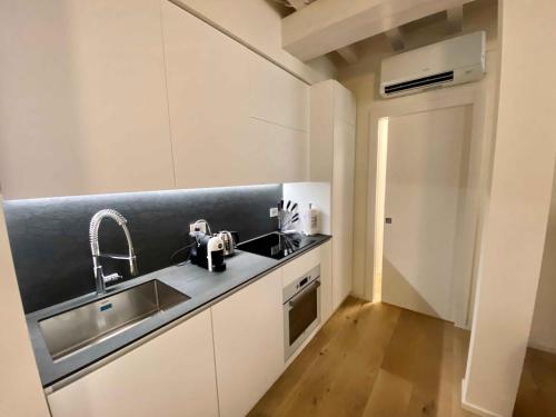 eine Küche mit weißen Schränken, einem Waschbecken und einem Waschbecken in der Unterkunft Volto Corte Farina Apartments - Luxury Lofts in Verona