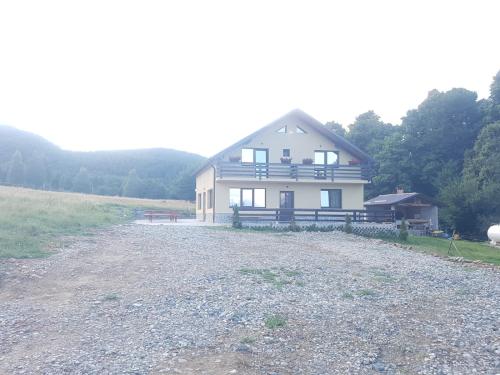 a large white house on a gravel road at Pensiunea Natura Sadu in Sibiu