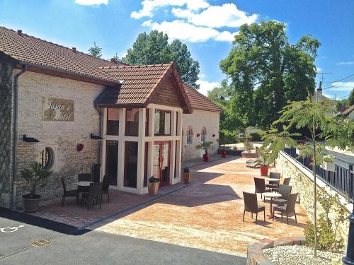 a building with chairs and tables outside of it at Logis Hostellerie la Chaumière in Arsonval