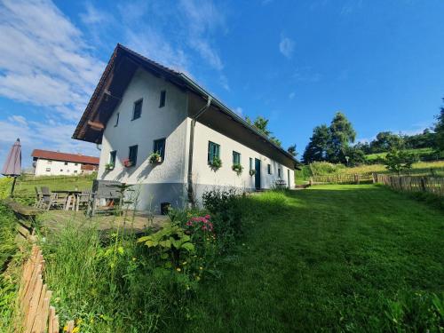 a white house with a grassy yard next to a building at Ferienhaus am Dachsberg, Bayerischer Wald in Haselbach