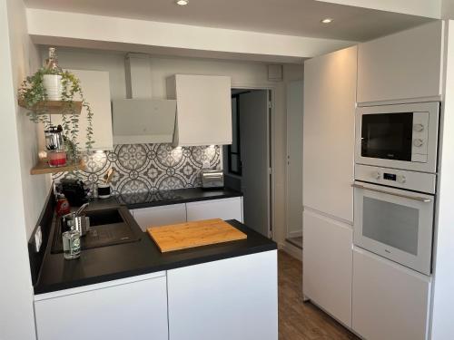 a kitchen with white cabinets and a black counter top at T3 Bis - 4 Etoiles Rooftop et Vue Mer - Bellevue Biarritz in Biarritz