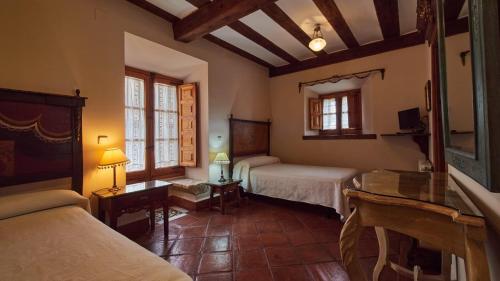 a bedroom with two beds and a table in a room at Posada de San Millán in Sepúlveda
