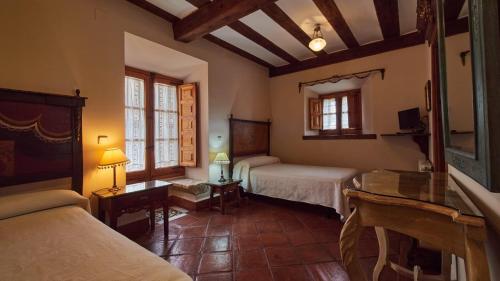 een slaapkamer met 2 bedden en een tafel in een kamer bij Posada de San Millán in Sepúlveda