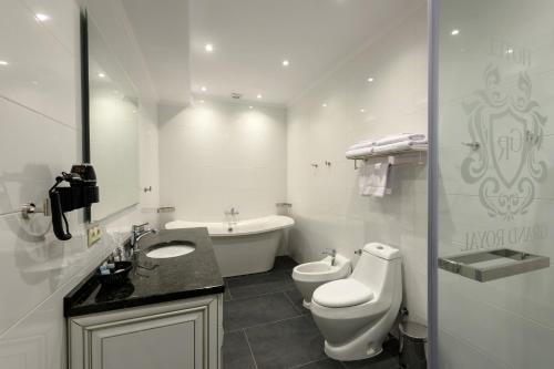 a white bathroom with a toilet and a sink at Grand Royal in Chernivtsi