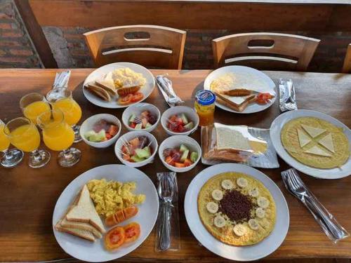 a table with plates of breakfast food and drinks at Alamanda Family Villas, Pool & Local Tours in Yogyakarta