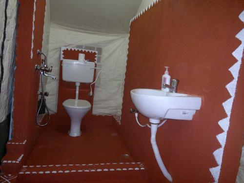 La salle de bains est pourvue d'un lavabo et de toilettes. dans l'établissement Nature Camp Konark Retreat, à Konârak