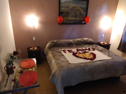 a bedroom with a bed and a table with flowers on it at Telpochcalli Hotel & Temazcal in San Juan Teotihuacán