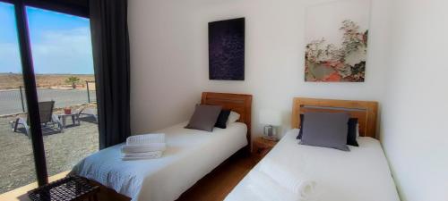 dwa łóżka w pokoju z oknem w obiekcie La Atalaya del Guirre w mieście Lajares