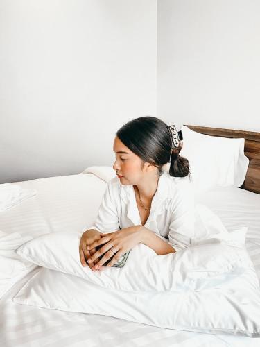 a woman sitting on a bed with her handsrequired at Play Poshtel & Cafe' in Krabi town