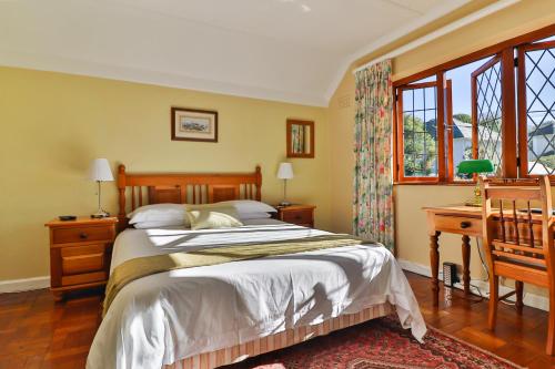 1 dormitorio con 1 cama, escritorio y ventanas en Knightsbury Guest House, en Ciudad del Cabo