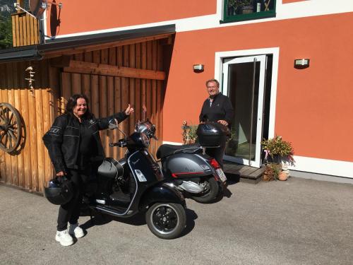 a man standing next to a scooter in front of a building at B&B Simmer in Obertraun