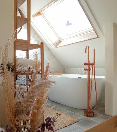 a bath tub in a bathroom with a skylight at Op Oost Boutique hotel & Restaurant het Kook Atelier in Oosterend