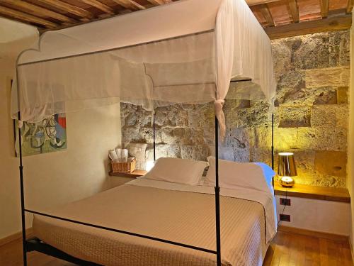 ein Schlafzimmer mit einem Himmelbett und einer Steinmauer in der Unterkunft TWIN TOWER - unica al mondo - unique in the world in San Gimignano